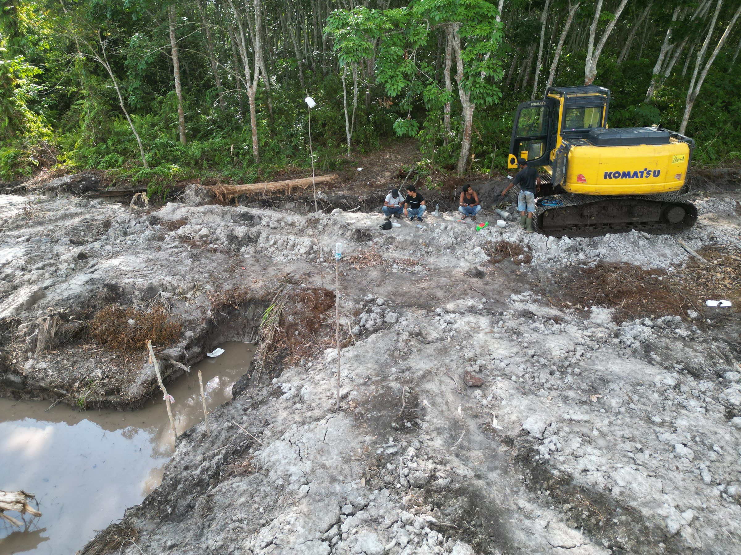 Excavator Komatsu di atas lahan yang sudah diratakan, dekat kolam galian